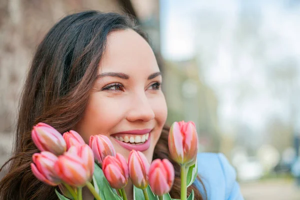 Mavi takım elbiseli, bir buket lale taşıyan güzel bir genç kadının portresi..