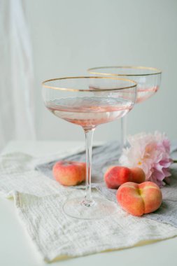 Pembe şampanyalı güzel bir bardak, fonda şeftali. Şakayıklar.