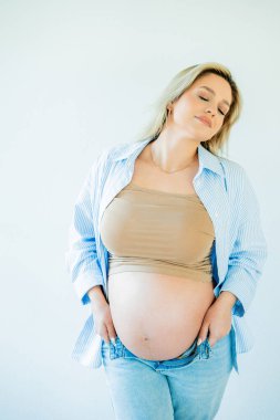 Genç, güzel, hamile bir kadın karnına sarılıyor. annelik.