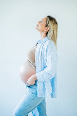 Genç, güzel, hamile bir kadın karnına sarılıyor. annelik.