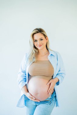 Genç, güzel, hamile bir kadın karnına sarılıyor. annelik.