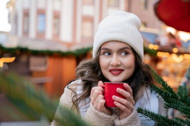 Genç mutlu kadın Noel pazarında sıcak içecek içiyor. Yeni yıl. Tatiller.
