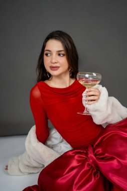 Yeni yıl konsepti. Altın pullu, elinde şampanya kadehi olan şenlikli elbiseli genç bir kadının portresi. Noel.