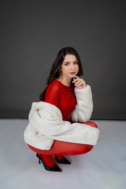 Yeni yıl konsepti. Elinde büyük kırmızı bir fiyonk olan, şenlikli elbiseli genç bir kadının portresi. Noel.