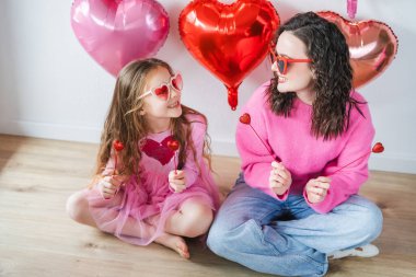 Pembe balonların arka planında kalp gözlüklü genç kız kardeşiyle çok tatlı bir kız. Sevgililer Günü. Doğum günü kutlaması.