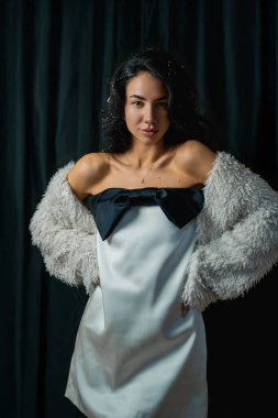 Siyah arka planda sahte kürk giyen genç bir kadının portresi. Kar yağışıName.