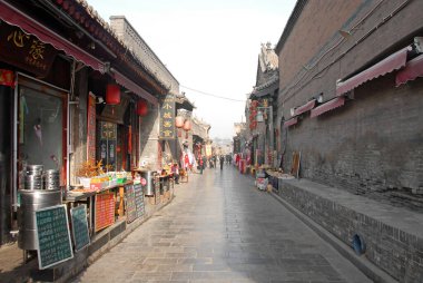 Pingyao in Shanxi Province, China:  A side street in Pingyao lined with restaurants and shops. Menu boards are in front of the restaurants. Pingyao old town is a famous ancient walled city in China.