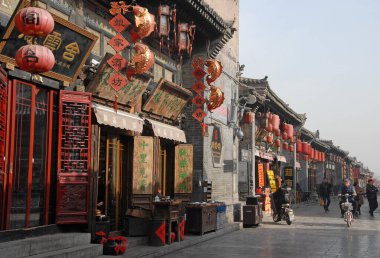 Pingyao, Shanxi Eyaleti, Çin: Pingyao 'da bir oteli, dükkanları ve mağazaları olan bir ana cadde. İnsanlar yürüyorlar ve scooterlara biniyorlar. Pingyao eski kasabası Çin 'de eski ve ünlü bir şehirdir..