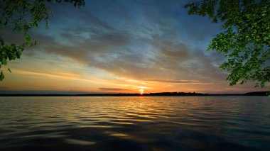 Volga 'da gün batımında nehir manzarası. Güneşin son ışınları gökyüzünü ve suyun yüzeyini turuncuya çevirdi..