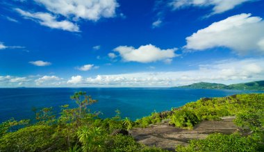 Güzel tropikal manzara, dağdan panoramik manzara, deniz ve uzak adaların turkuaz yüzeyinde yeşilliklerle kaplı. Seyşeller. Praslin Adası.