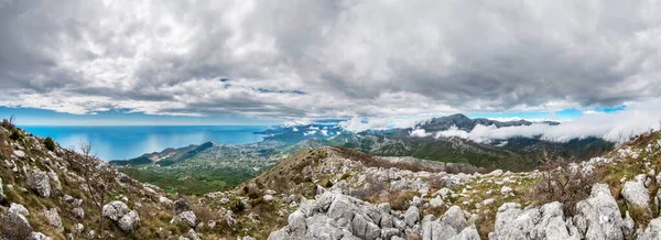 Rumia Dağı 'nın tepesinden panoramik manzara. Alçak bulutlar dağları kısmen kaplıyor. Karadağ.