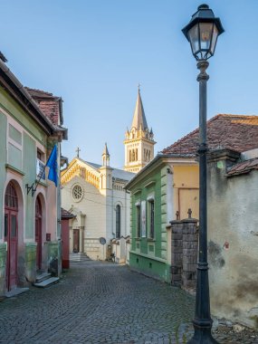 Sighisoara Romanya - 11.26.2020: Saint Joseph manzarası (Sf. Iosif) Katolik Kilisesi Sighisoara Kalesi 'nin kaldırım taşı sokaklarından.