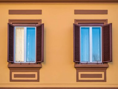 Romanya 'nın Sighisoara kentindeki turuncu bir duvarda eski ahşap panjurlar bulunan bir pencerenin ayrıntıları.