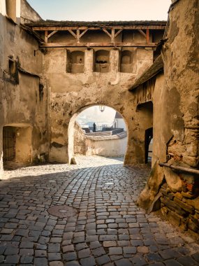 Romanya 'daki Sighisoara kalesinin duvarları arasındaki kaldırım taşı caddesi.