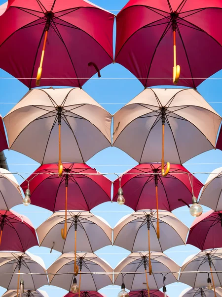 Suspended colored umbrellas and light bulbs against blue sky. — Stock Image Suspended Colored Umbrellas Light Bulbs Blue Sky Royalty Free Stock Images