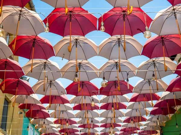 Suspended colored umbrellas and light bulbs against blue sky. — Stock Image Suspended Colored Umbrellas Light Bulbs Blue Sky Stock Image