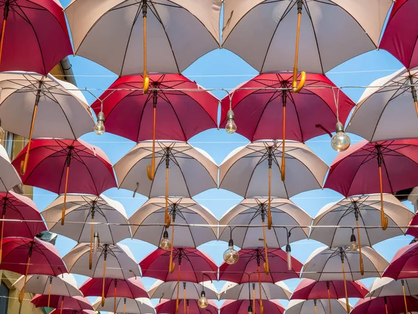 Suspended colored umbrellas and light bulbs against blue sky. — Stock Image Suspended Colored Umbrellas Light Bulbs Blue Sky Stock Image