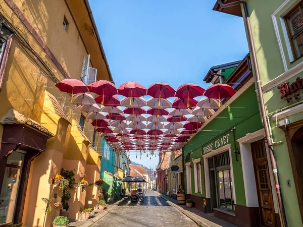 Sighisoara Romania - 11.26.2020: Suspended umbrellas over a cobblestone street in Sighisoara — Stock Image Sighisoara Romania 2020 Suspended Umbrellas Cobblestone Street Sighisoara Stock Photo