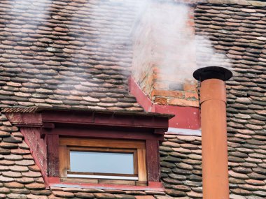Kırsal alan, eski kırmızı kiremit çatılı bir evin bacasından yükselen dumanla birlikte.