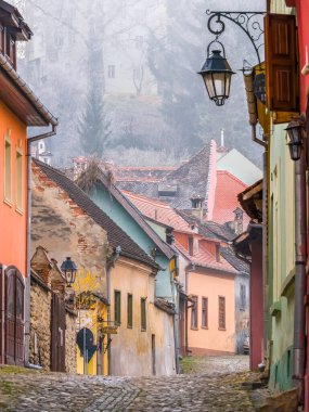 Sighisoara Romanya - 11,26,2020: Romanya 'da kaldırım taşı sokakları ve Sighisoara Ortaçağ Kalesi' nin eski binaları ile sahne.