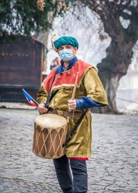 Sighisoara Romanya - 11.26.2020: Boynunda davul asılı ortaçağ kostümü giymiş bir adam. Sighisoara 'da ortaçağ davulcusu.