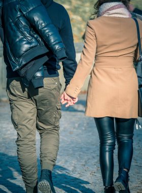 Çekici genç bir çift kaldırım taşı caddesinde yürürken el ele tutuşuyorlar.