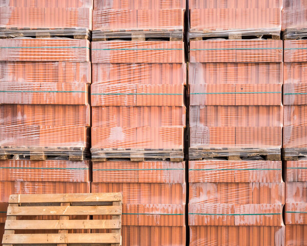 Red bricks for construction buildings stacked on wooden pallets