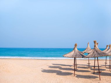 Summer landscape with straw umbrellas on the beach in Mangalia or Mamaia. Beach at the Black Sea in Romania.