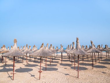 Summer landscape with straw umbrellas on the beach in Mangalia or Mamaia. Beach at the Black Sea in Romania.