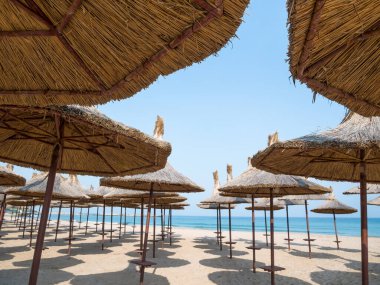 Summer landscape with straw umbrellas on the beach in Mangalia or Mamaia. Beach at the Black Sea in Romania.