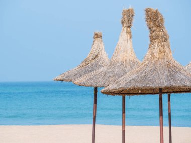 Summer landscape with straw umbrellas on the beach in Mangalia or Mamaia. Beach at the Black Sea in Romania.