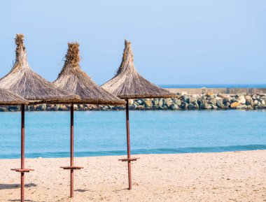 Summer landscape with straw umbrellas on the beach in Mangalia or Mamaia. Beach at the Black Sea in Romania.