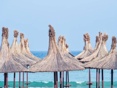 Summer landscape with straw umbrellas on the beach in Mangalia or Mamaia. Beach at the Black Sea in Romania.