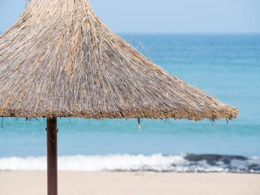 Summer landscape with straw umbrellas on the beach in Mangalia or Mamaia. Beach at the Black Sea in Romania.