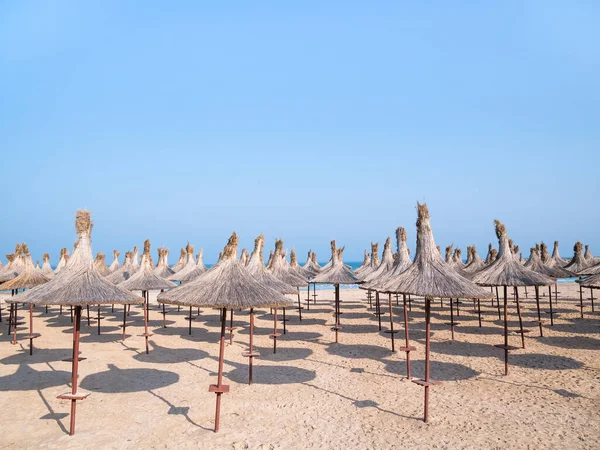 Summer landscape with straw umbrellas on the beach in Mangalia or Mamaia. Beach at the Black Sea in Romania.