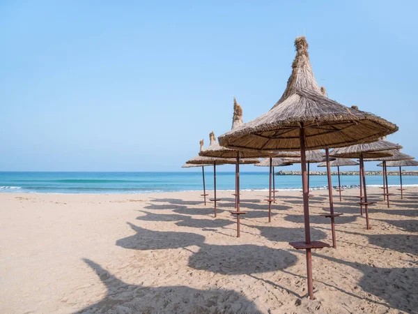 Summer landscape with straw umbrellas on the beach in Mangalia or Mamaia. Beach at the Black Sea in Romania.