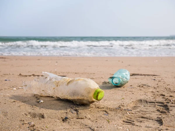 A PET plastic bottle left on the sandy beach. Plastic pollution environment concept.