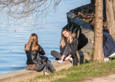 Bükreş, Romanya - 03.26.2021: King Mihai I Park 'ta gölün kenarında poz veren çekici genç kız (herestrau)