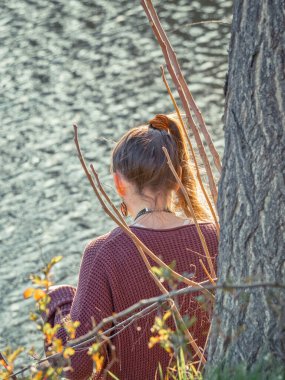 Bir gölün kenarında oturmuş meditasyon yapan genç bir kız.