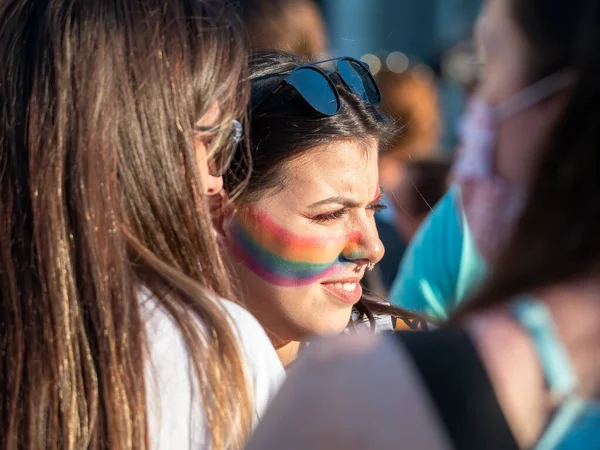 Bükreş, Romanya - 08.14.2021: Septum piercingli güzel bir kız ve LGBTQ Onur Yürüyüşü mitinginde yüzünde gökkuşağı bayrağı resmi .