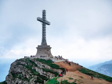 Busteni, Romanya - 07.10.2021: Romanya 'nın Bucegi Dağları' ndaki Caraiman zirvesinde Kahramanlar Haçı ile manzaraya bakın.