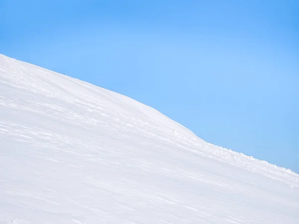 澄んだ青空に白い雪に覆われた山の詳細 登山道の新雪に足を踏み入れると 真っ青な空に白い雪に覆われた山が広がります トレイルの新雪の中の足跡 — ストック写真