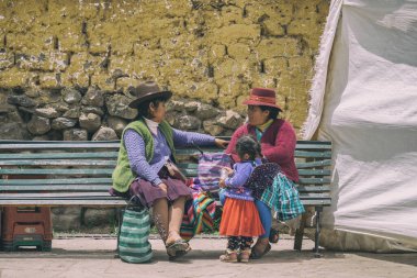 Ollantaytambo, Peru - 17 Mart 2025: Ollantaytambo kasabasında bir bankta oturan iki yaşlı Perulu kadın