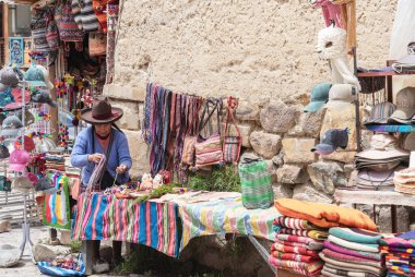 Ollantaytambo, Peru - 17 Mart 2025: Ollantaytambo Arkeoloji Sitesi 'nin girişinde geleneksel Peru hatıraları satan yaşlı kadın