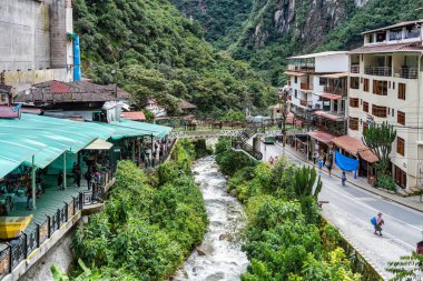 Aguas Calientes, Peru - 18 Mart 2025 Aguas Calientes 'ten yaya köprüleri ve nehir kenarındaki geçitlerden canlı renkli bir manzara.