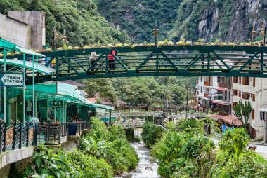 Aguas Calientes, Peru - 18 Mart 2025 Aguas Calientes 'ten yaya köprüleri ve nehir kenarındaki geçitlerden canlı renkli bir manzara.