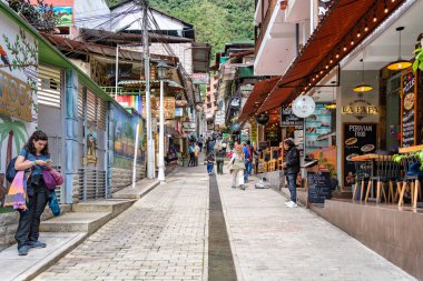 Aguas Calientes, Peru - 18 Mart 2025: Aguas Calientes 'ten yerel satıcılar, dükkanlar ve turistlerle birlikte yaya sokak sahnesi.