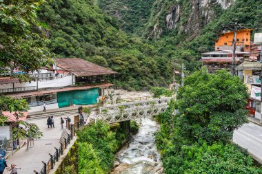 Aguas Calientes, Peru - 18 Mart 2025 Aguas Calientes 'ten yaya köprüleri ve nehir kenarındaki geçitlerden canlı bir manzara.