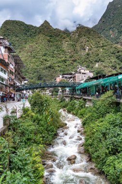 Aguas Calientes, Peru - 18 Mart 2025 Aguas Calientes 'ten yaya köprüleri ve nehir kenarındaki geçitlerden canlı bir manzara.