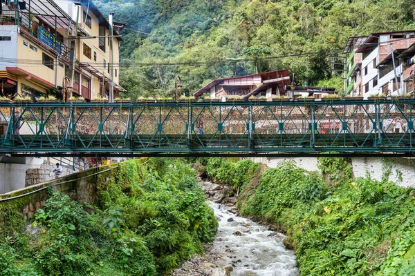 Aguas Calientes, Peru - 18 Mart 2025 Aguas Calientes 'ten yaya köprüleri ve nehir kenarındaki geçitlerden canlı bir manzara.